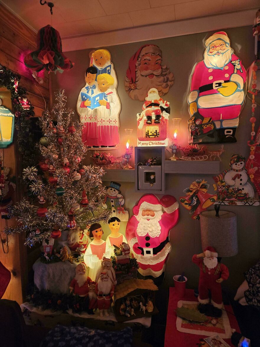 Nostalgic vintage Christmas decorations including illuminated Santas, carolers, and a silver tinsel tree in a cozy room.