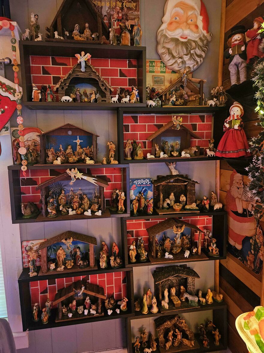 Vintage Christmas decorations featuring multiple nativity scenes arranged on wooden shelves with nostalgic holiday decor surrounding them.