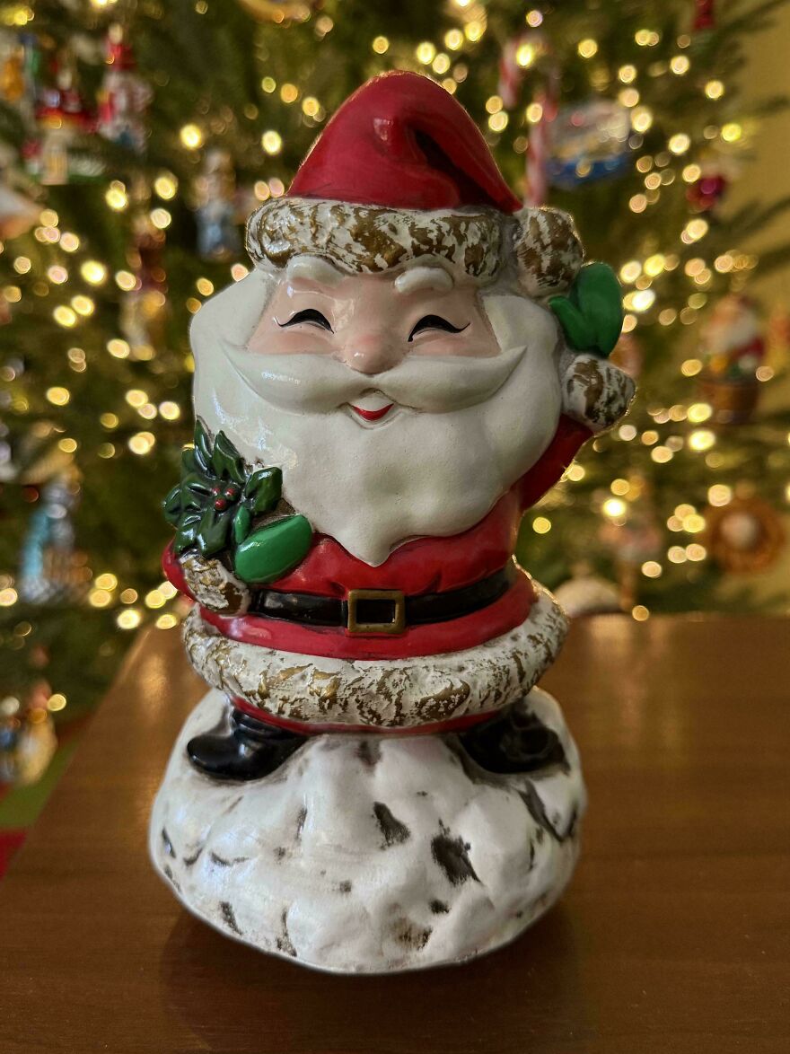 Vintage Christmas decoration of a smiling Santa Claus figurine with holiday lights and tree in the background