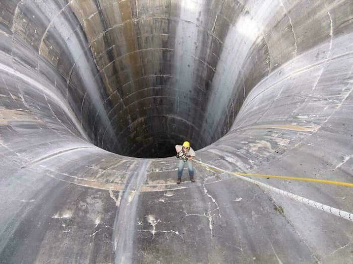 Person rappelling down a massive concrete structure, illustrating fear related to megalophobia and extreme height.