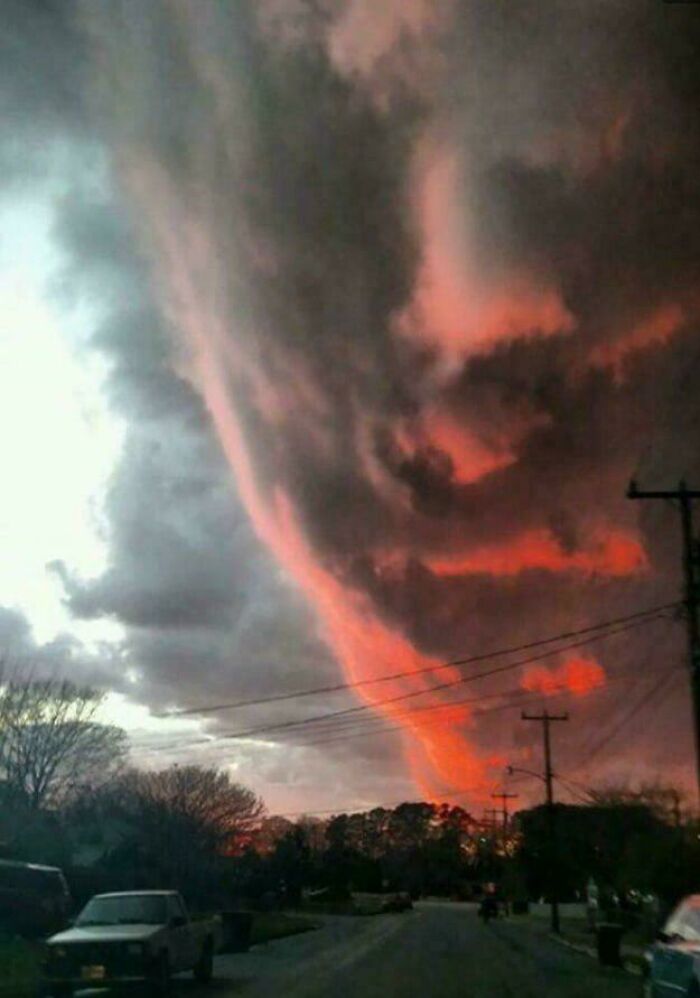 Massive ominous dark clouds with glowing red hues over a suburban street, triggering megalophobia fear of large objects.