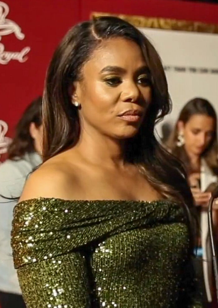 Regina Hall attending an event wearing a sparkling green off-shoulder dress, showcasing her bio and career highlights.