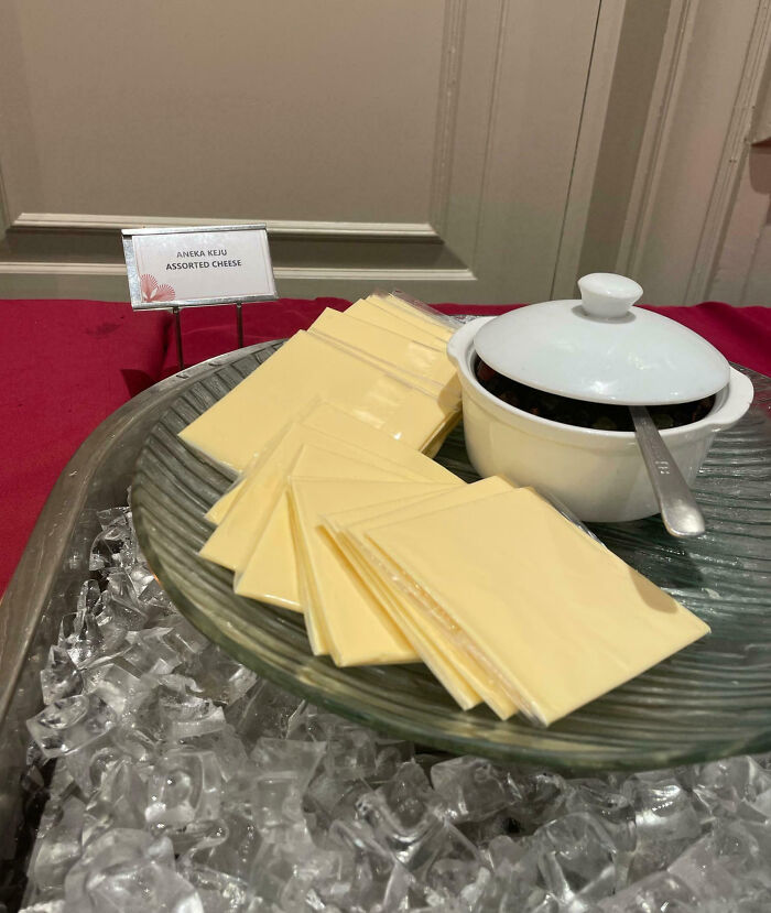 Assorted sliced cheese and a covered bowl on a plate over ice, an example of outrageous meals that look unlike menu photos.