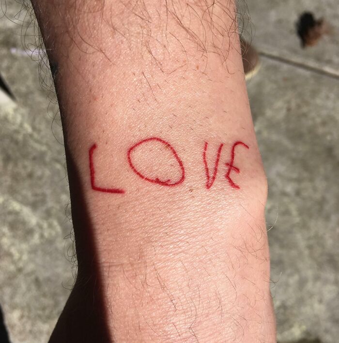 Close-up of a wholesome tattoo on wrist spelling love in red ink, showcasing meaningful small ink design. Close-up of a wholesome tattoo on wrist spelling love in red ink, showcasing meaningful small ink design.