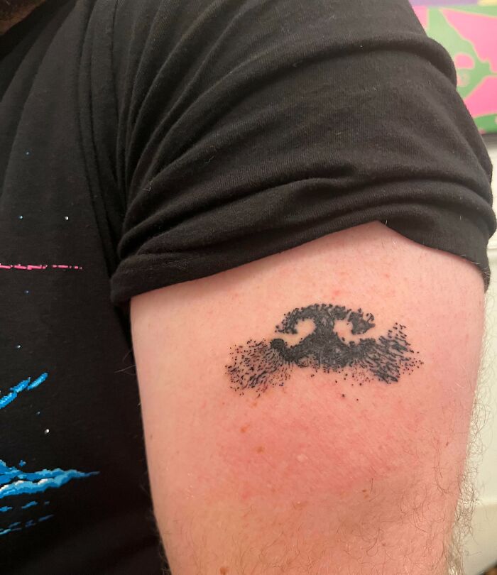 Small black ink tattoo of a stylized wave on the upper arm showcasing meaningful wholesome tattoos. Small black ink tattoo of a stylized wave on the upper arm showcasing meaningful wholesome tattoos.