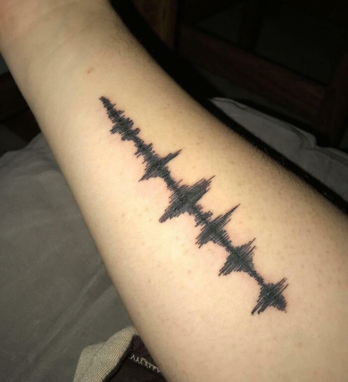 Close-up of a forearm with a wholesome tattoo of a soundwave design symbolizing meaningful ink art.