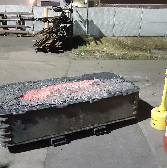 A heated welding table with metal beams stacked nearby in an industrial job setting for 9-to-5 workers.