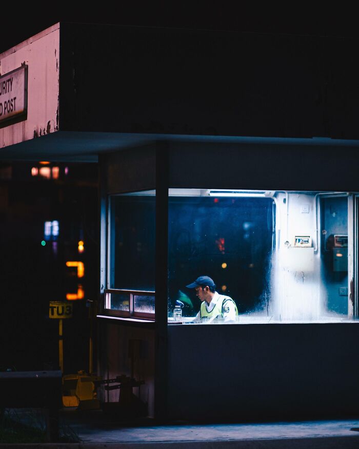 Security guard working alone in a dimly lit booth at night, showcasing unique jobs that make a 9-to-5 more bearable.