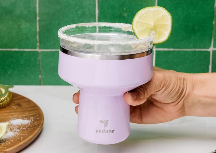Hand holding a lavender insulated cup with salted rim and lime slice, a unique never-before-seen gift idea.