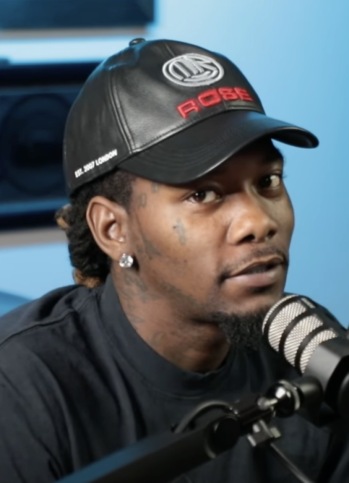 Offset wearing a black cap and diamond earring speaking into a microphone in a recording studio setting for a bio and career highlights interview.