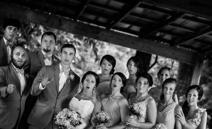 Group of bridesmaids and groomsmen in wedding attire captured in a funny and interesting moment at the perfect time.