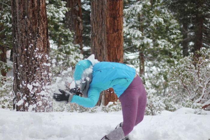 Person in a blue jacket and purple pants falling backward while snow explodes, captured in a funny perfect timing pic.
