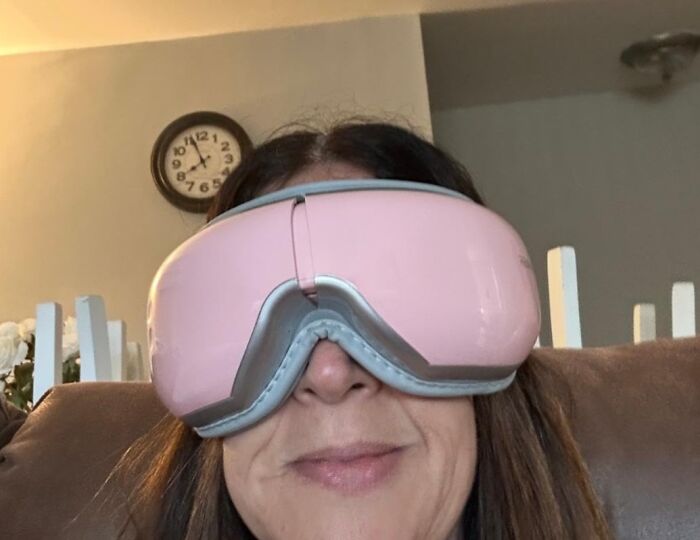 Woman using a pink eye massager as a useful present to secure favorite child status with practical gifts.