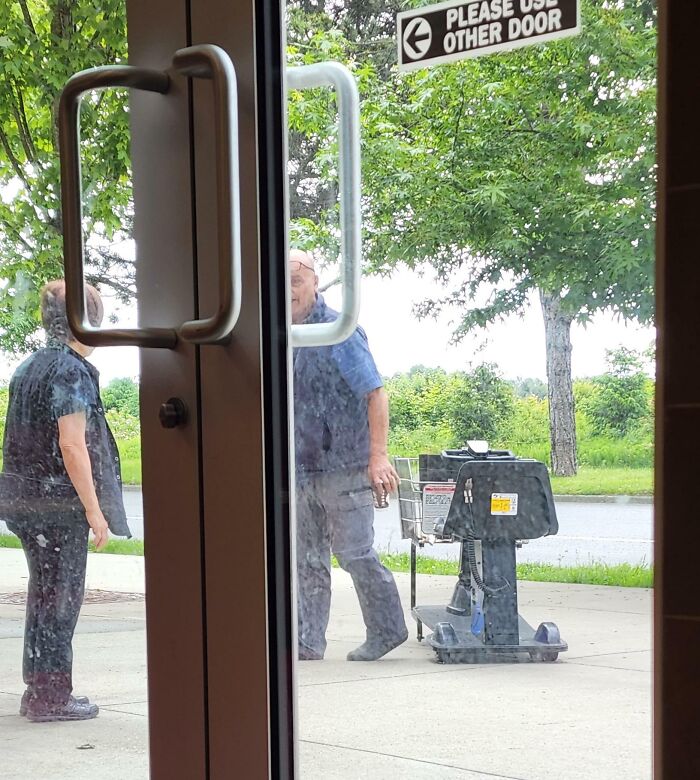 Two men outside a Walmart store near a cleaning machine with a sign directing to please use the other door.