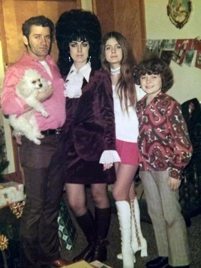 Family posing in awkward vintage Christmas photo with 70s fashion and distinct hairstyles, capturing hilarious holiday moments.