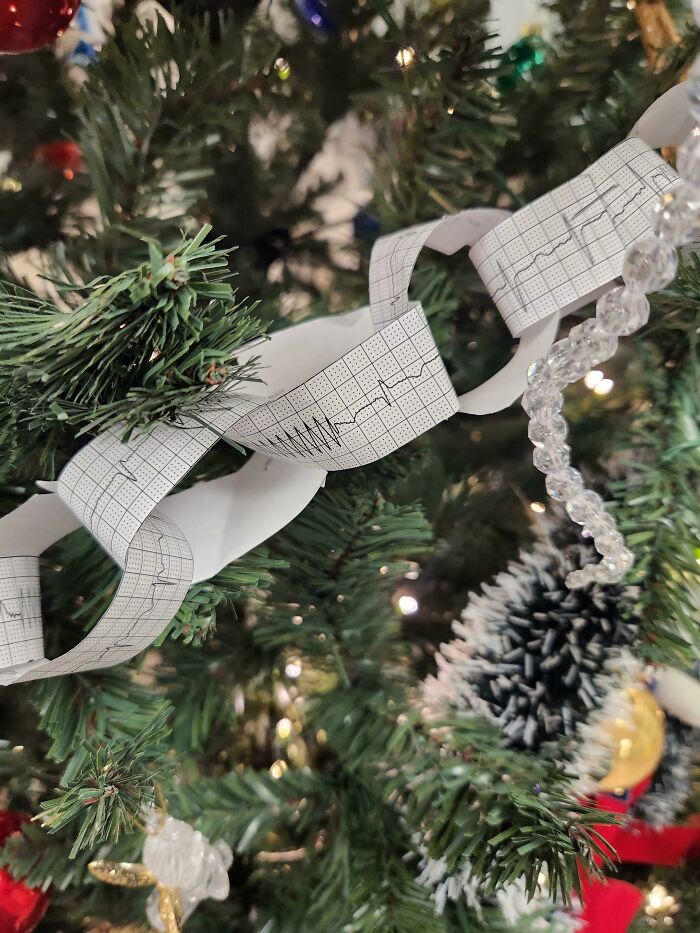 Creative workplace Christmas decorations featuring a paper garland with heartbeat patterns on a festive tree branch.