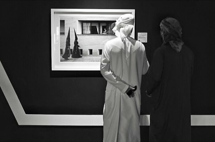 Two men in traditional clothing observing a black and white photograph capturing street moments that feel like magic.