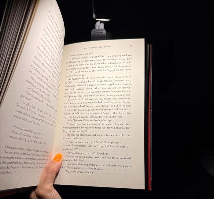 Open book being illuminated by a small reading light, ideal for last-minute guest gift inspiration.