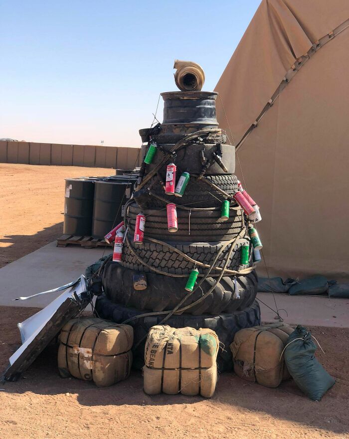 Creative workplace Christmas decoration made from stacked tires and cans outdoors in a desert setting.