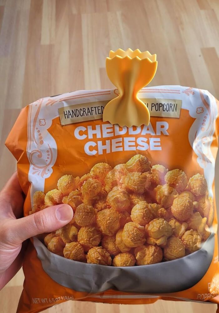 Hand holding a bag of cheddar cheese popcorn, a perfect gift for last-minute guests this holiday season.