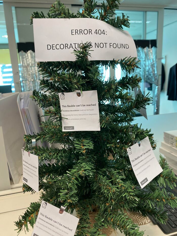 A creative workplace Christmas decoration with error 404 signs on a small tree, showing a humorous tech theme.