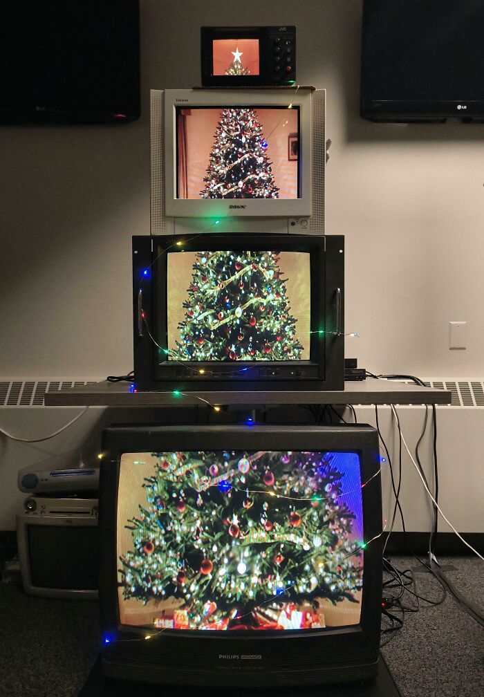 Creative workplace Christmas decorations featuring stacked vintage TVs displaying decorated Christmas trees with festive lights.