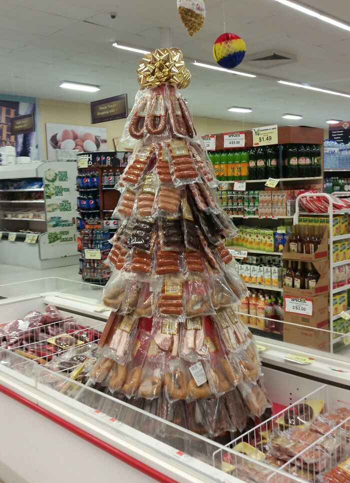 Creative Christmas decoration in a grocery store featuring a festive tree made of packaged meats impressing Santa.