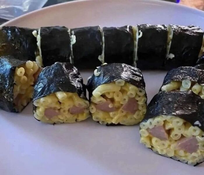 Unappetizing food pic of sushi rolls made with macaroni and hot dog pieces wrapped in seaweed.