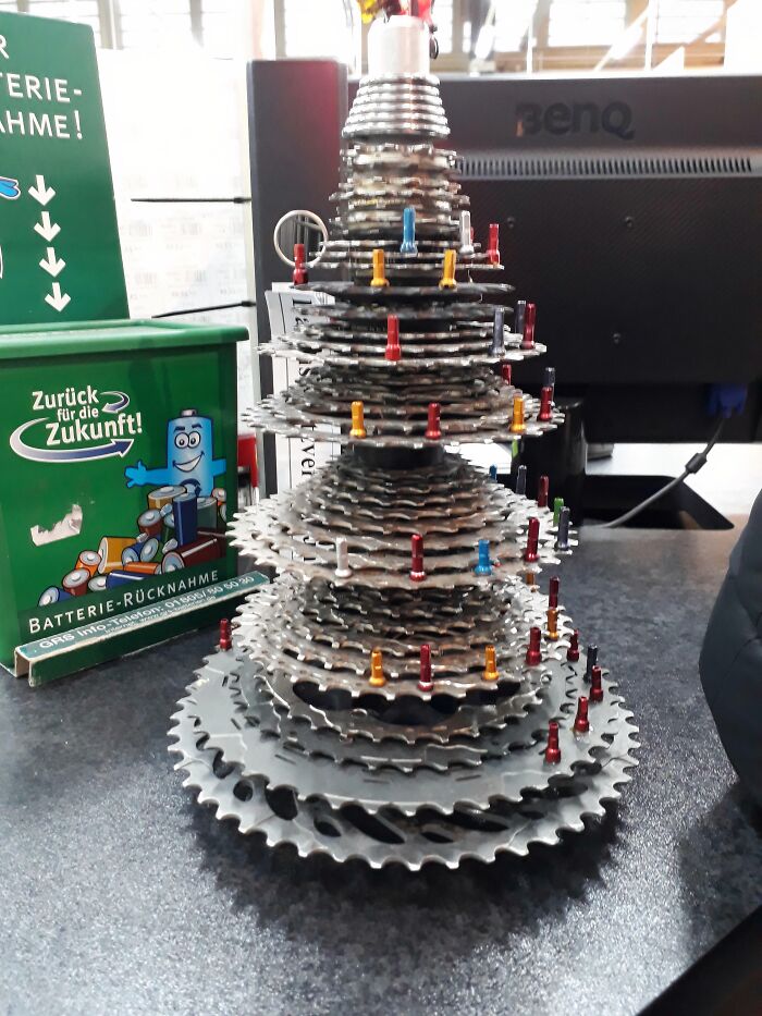 Creative Christmas decoration at workplace made from stacked metal gears resembling a festive tree with colorful pins.
