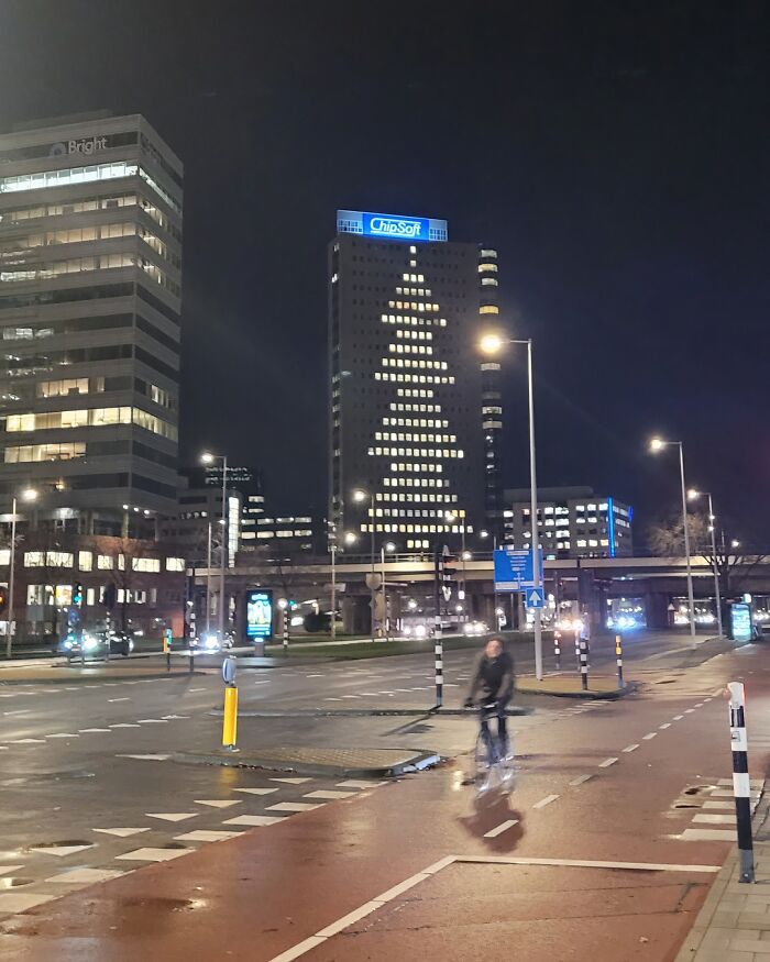 Office building windows lit up in a creative Christmas decoration shaped like a tree, showcasing festive workplace spirit.