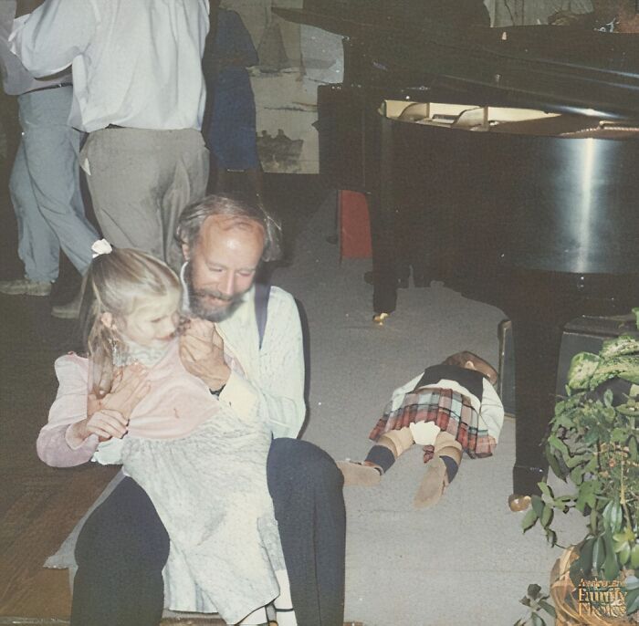 Man and child sharing a tender moment on the floor during a hilariously awkward family Christmas photo.