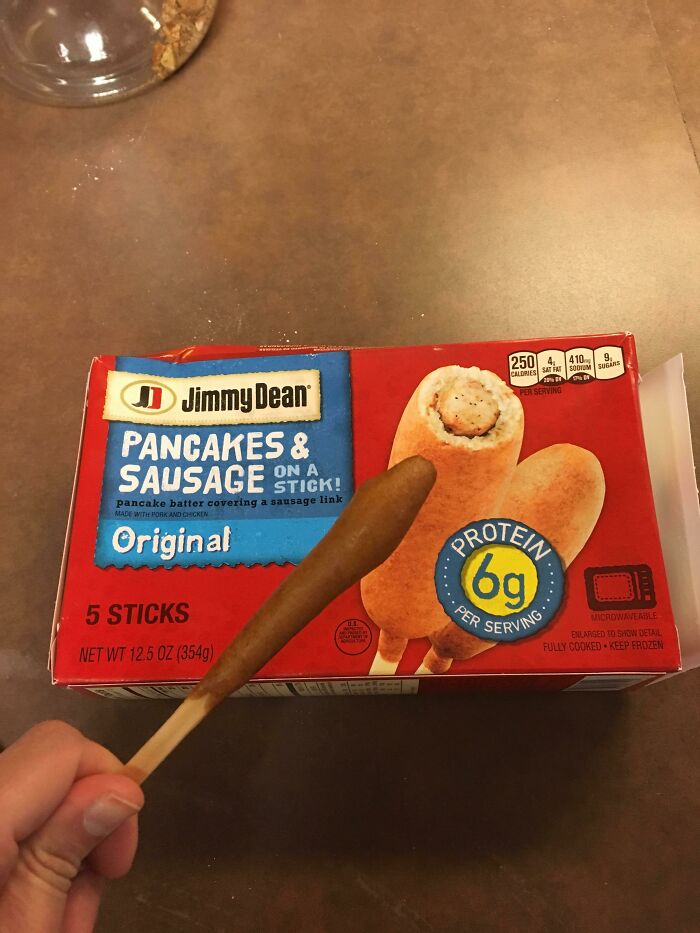 Person holding a tiny pancake and sausage stick next to the product box showing expectations vs reality photos.