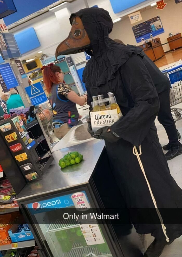 Person in a plague doctor costume holding beer inside a Walmart store, creating a strange and unusual Walmart moment.