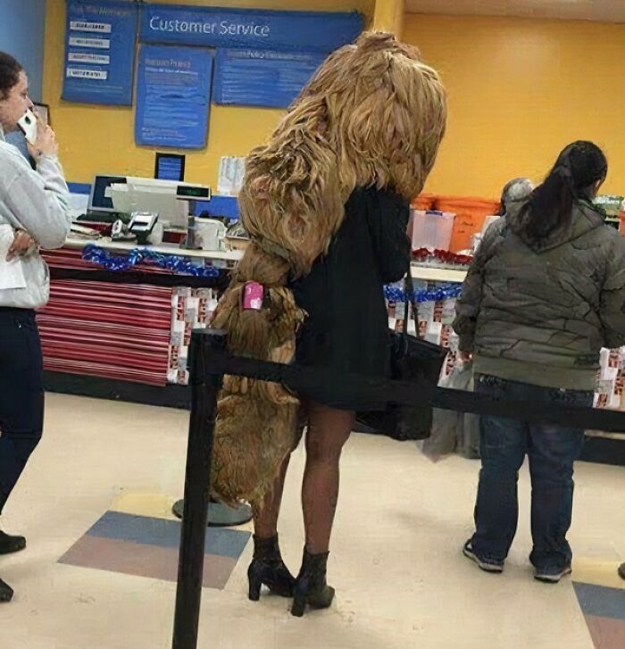 Person wearing an unusual large furry costume standing in line at Walmart customer service area.
