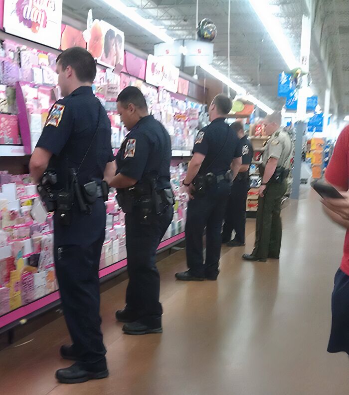 Police officers lined up browsing Valentine's Day cards inside a Walmart store, creating a curious scene.