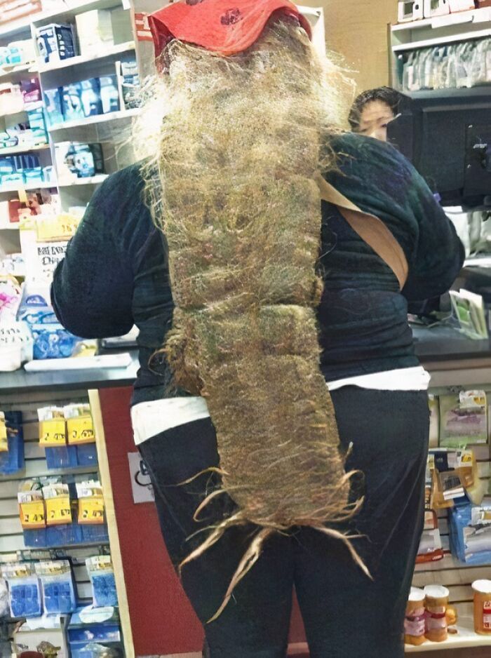 Person with an extremely long and tangled beard shopping inside a Walmart store near the checkout counter.