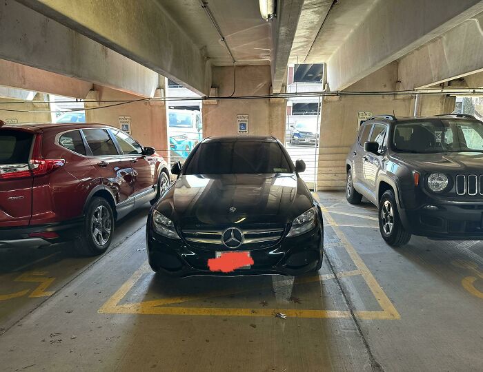 Black Mercedes parked over two handicap spots in a garage, an example of next-level jerks