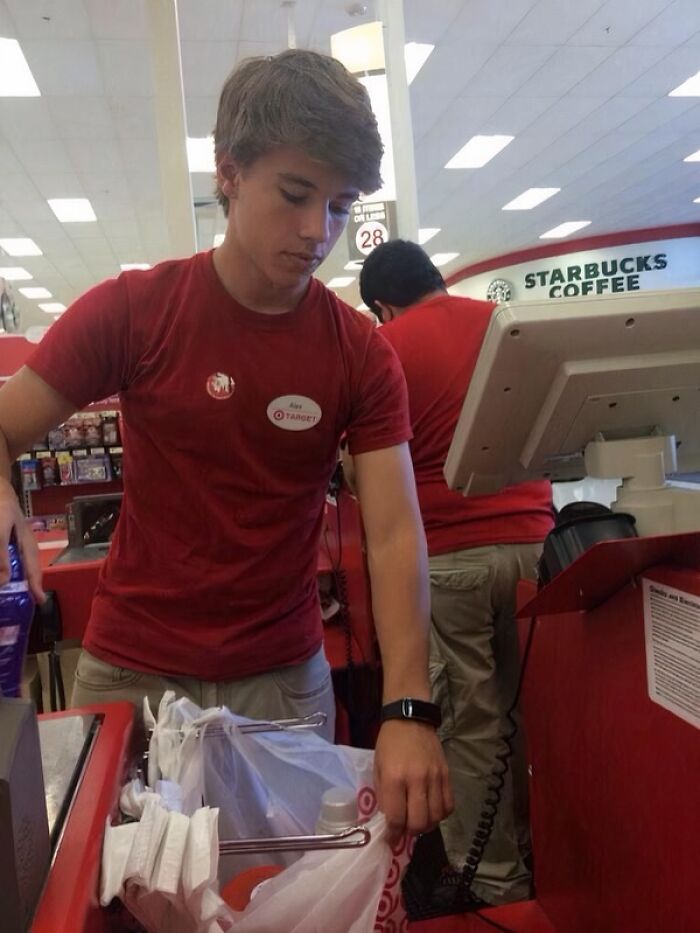 Young Target employee packing groceries at checkout counter, a viral moment turning him into an internet icon.
