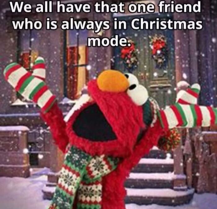 Red puppet character wearing striped Christmas scarf and mittens, joyful in a snowy street, showing funny Christmas memes humor.