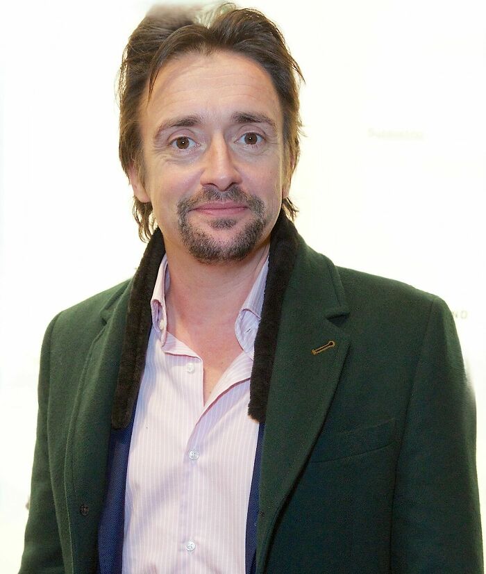 Richard Hammond smiling at an event, wearing a green coat and light pink shirt, showcasing his bio and career highlights.