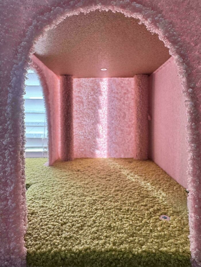 Pink and yellow textured room resembling a liminal space with an arched entrance and soft lighting, evoking backrooms atmosphere.