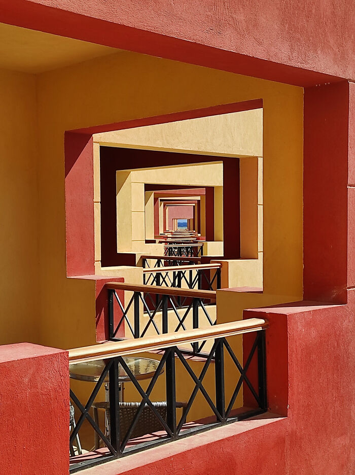Geometric liminal spaces with repeating red and yellow frames and black railings creating a backrooms-like effect.