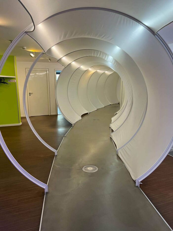 Curved corridor with white fabric sections creating liminal spaces that resemble creepy backrooms in an indoor setting.