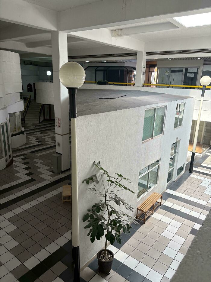 Empty liminal space with tiled floors, white walls, and minimal lighting that looks like the backrooms in a building interior.