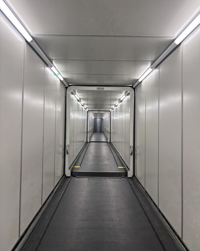 Empty dimly lit liminal space corridor with white walls and fluorescent lights resembling the backrooms atmosphere.