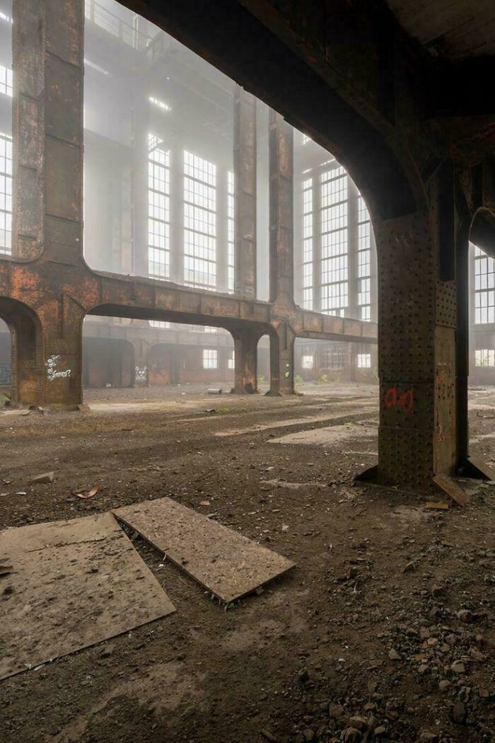 Abandoned industrial liminal space with large windows and rusty pillars, resembling creepy backrooms atmosphere.