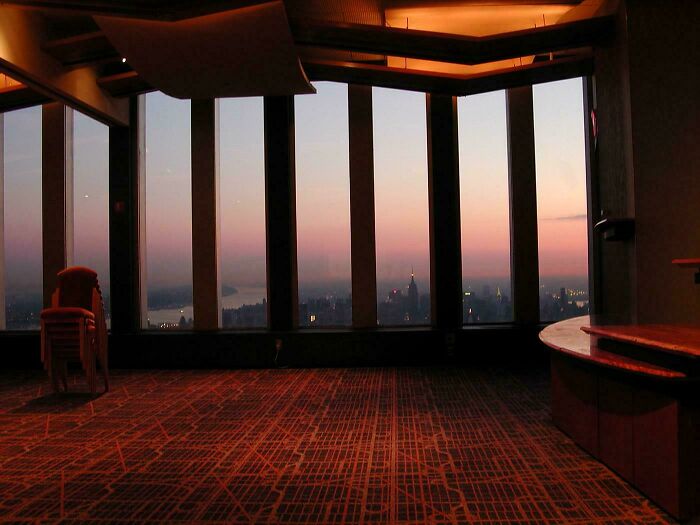 Empty room with large windows at dusk, showcasing a liminal space that looks like the backrooms with urban skyline views.