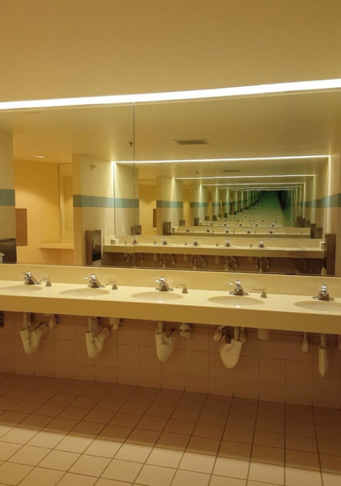Public restroom sinks with endless mirror reflections creating a creepy liminal space resembling the backrooms atmosphere.