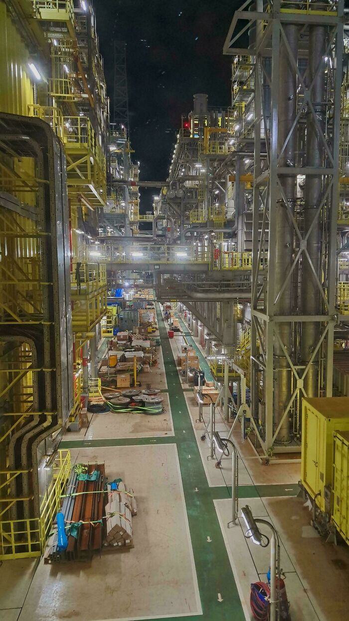 Industrial liminal space with metal structures and pipes at night, resembling eerie backrooms atmosphere.