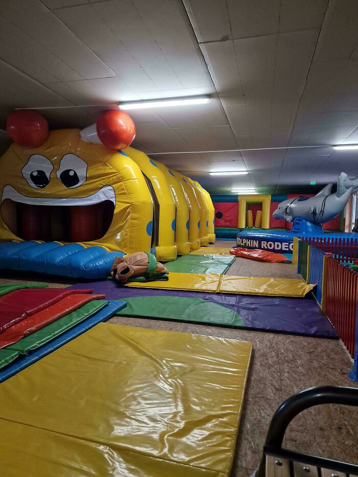 Inflatable play area with colorful mats and toys in a dimly lit room resembling liminal spaces.